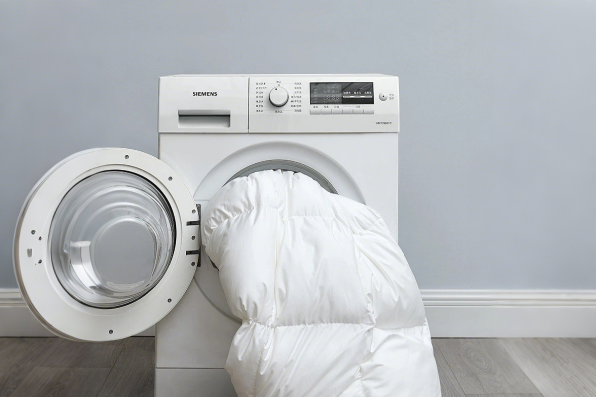 White Apsmile down comforter being placed into a front-loading washing machine, showcasing the daily care of this fluffy, comfortable bedding item