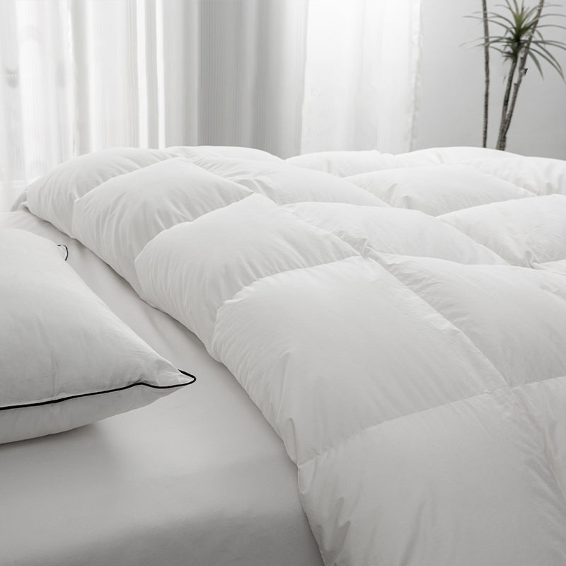 Close-up of an APSMILE white down comforter and pillow on a bed with a white sheet.