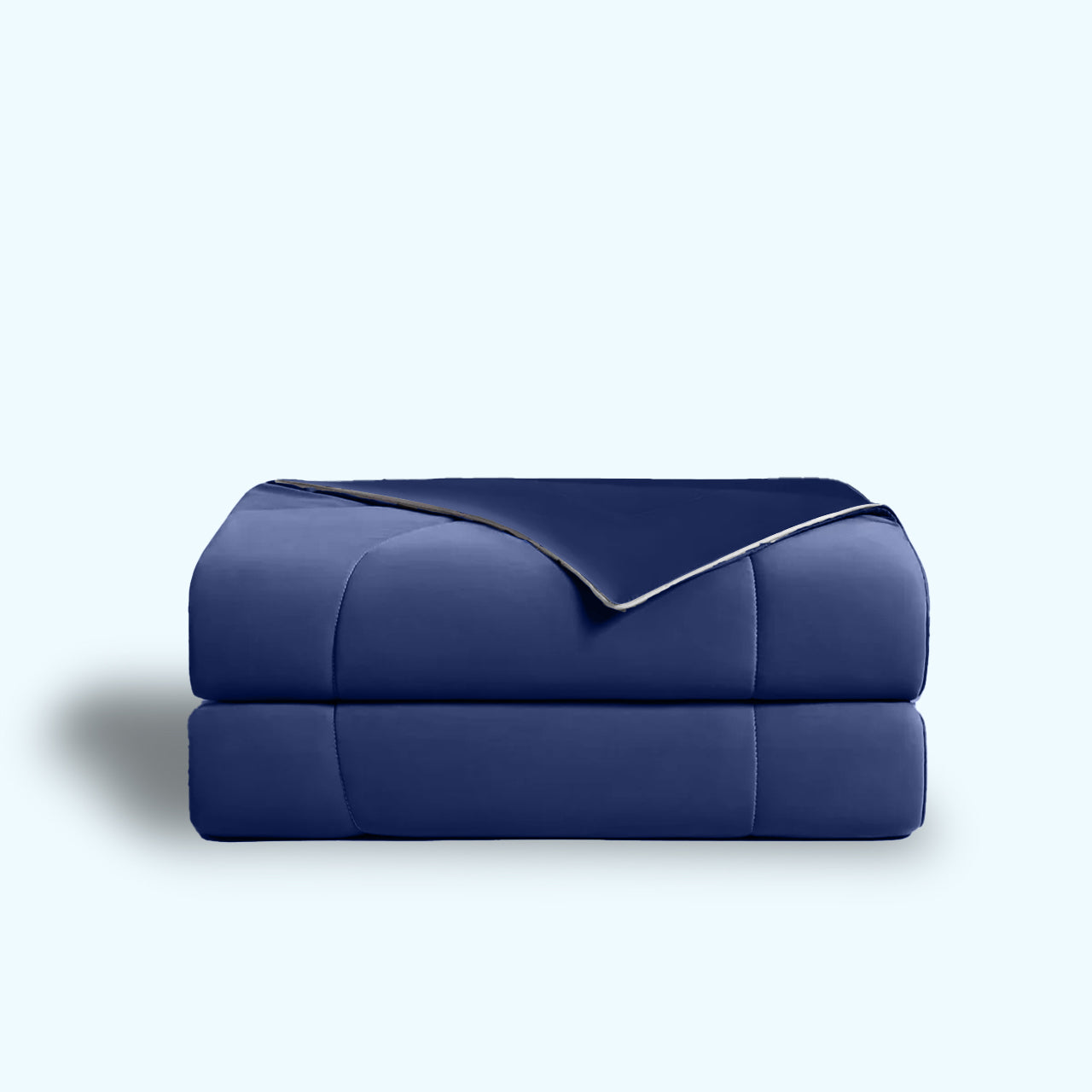 Navy blue quilted comforter, folded in half, against a light blue background.