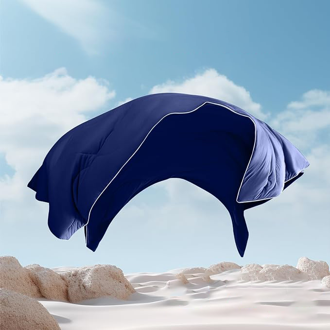 Navy blue APSMILE cooling blanket with white trim floating over a sandy landscape against a blue sky.