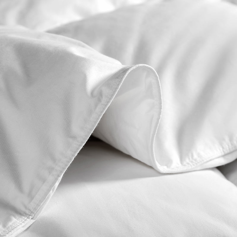 Close-up on the folded edge of a bright white APSMILE down comforter.