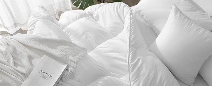Close-up of a white quilted duvet with a book titled "brombear" and a thin white blanket.