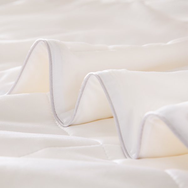 Close-up of an APSMILE bamboo fiber blanket, displaying the soft white fabric and quilted construction.