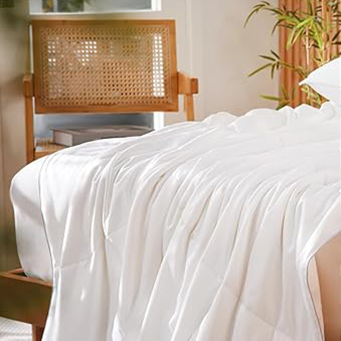 Close-up view of an APSMILE bamboo fiber comforter on a bed with a woven-cane headboard and greenery in the background.