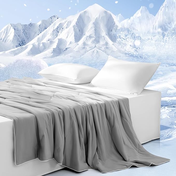 Gray APSMILE cooling blanket draped over a white bed with pillows, set against a backdrop of snow-capped mountains under a blue sky.