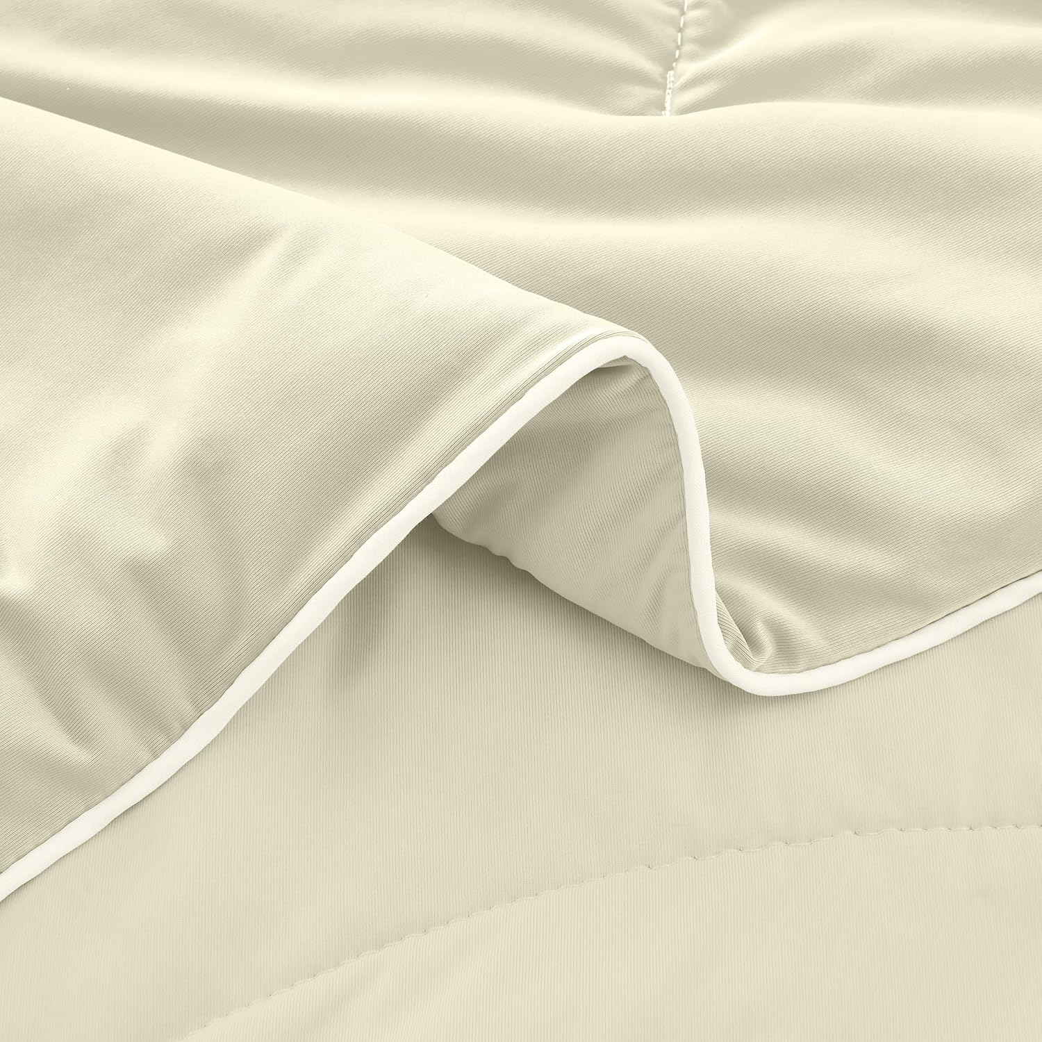 Close-up of a folded, light-yellow comforter with white piping.