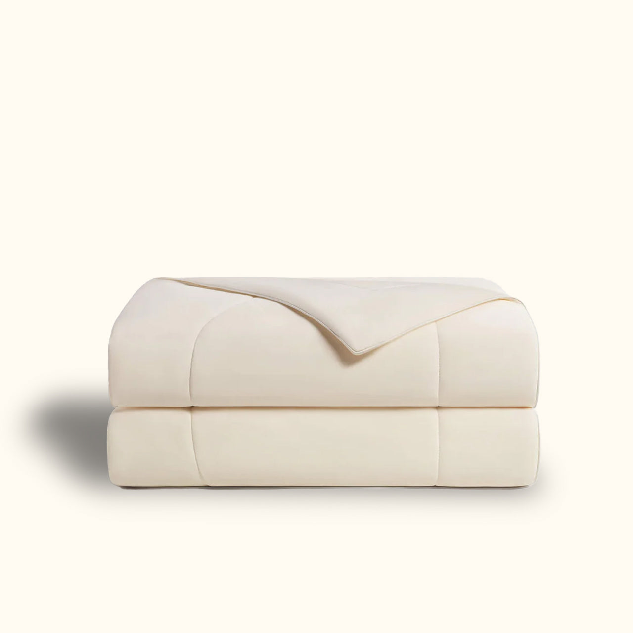 Folded ivory comforter on white background.