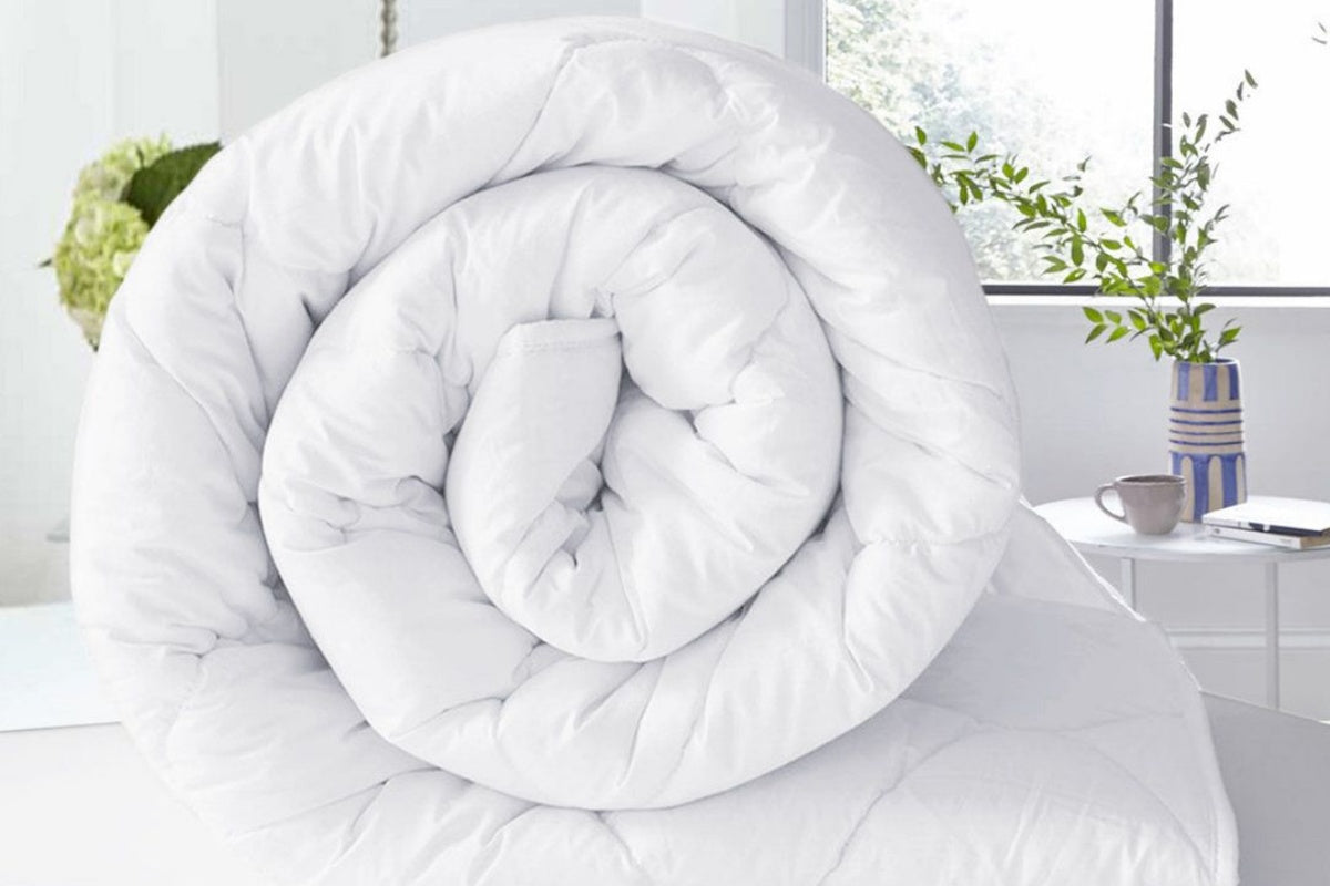 A rolled white duvet in a bright, tidy room, related to how to clean a duvet.