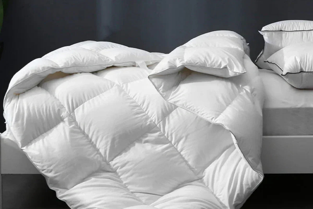 APSmile down comforter draped over a bed, with matching APSmile pillows featuring a black border.