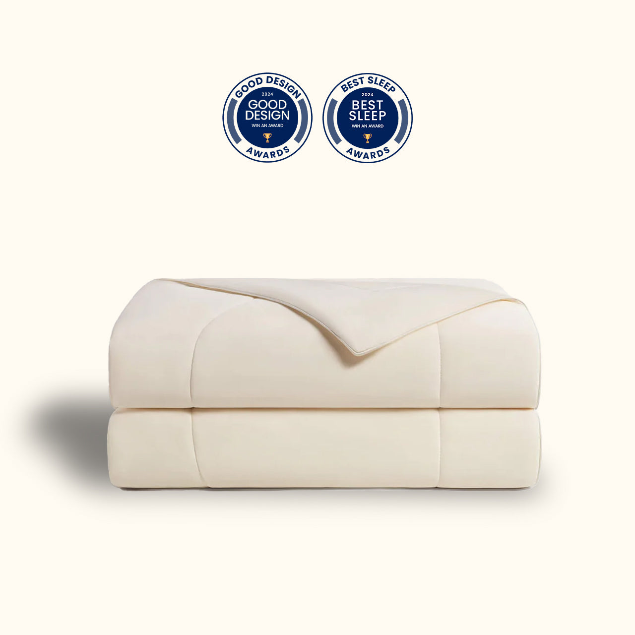 Ivory-colored duvet folded and stacked, presented against a plain background, and adorned with seals indicating recognition with design and sleep awards.
