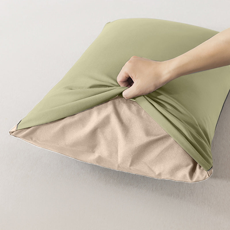 Hand pulling light green pillowcase away from tan pillow.