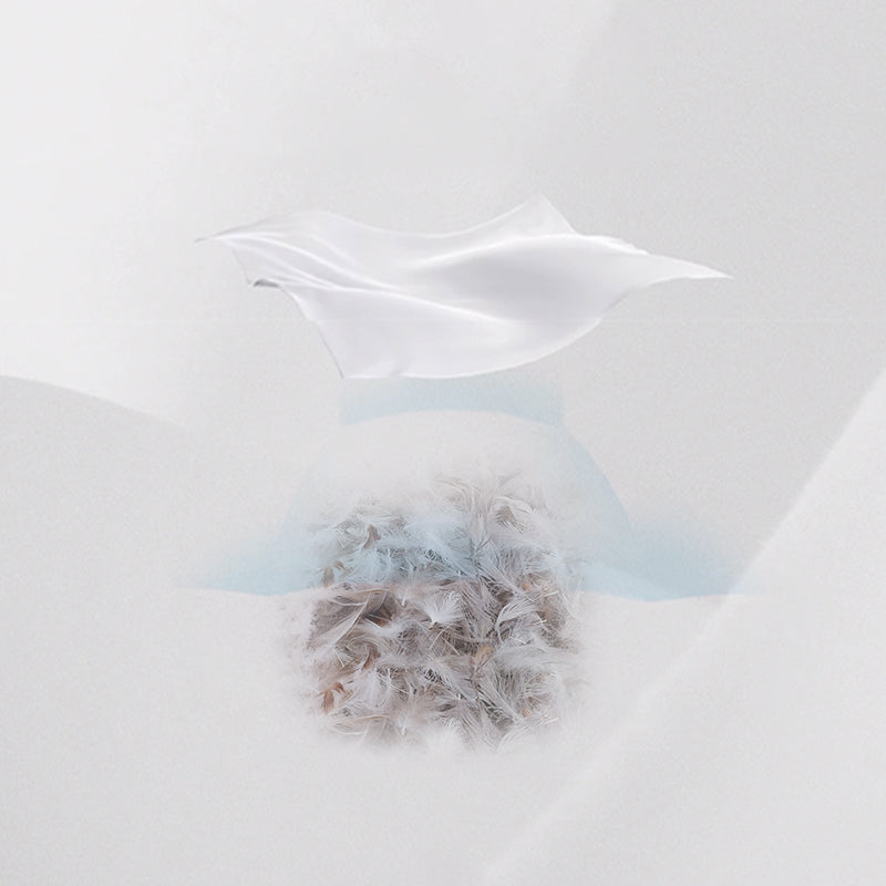 White fabric drapes gracefully above a cluster of feathers, all against a minimalist white setting.