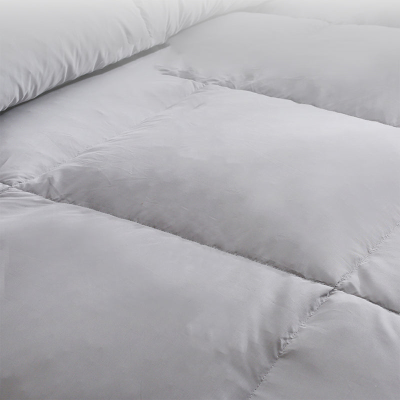 Close-up of a puffy, light gray comforter.