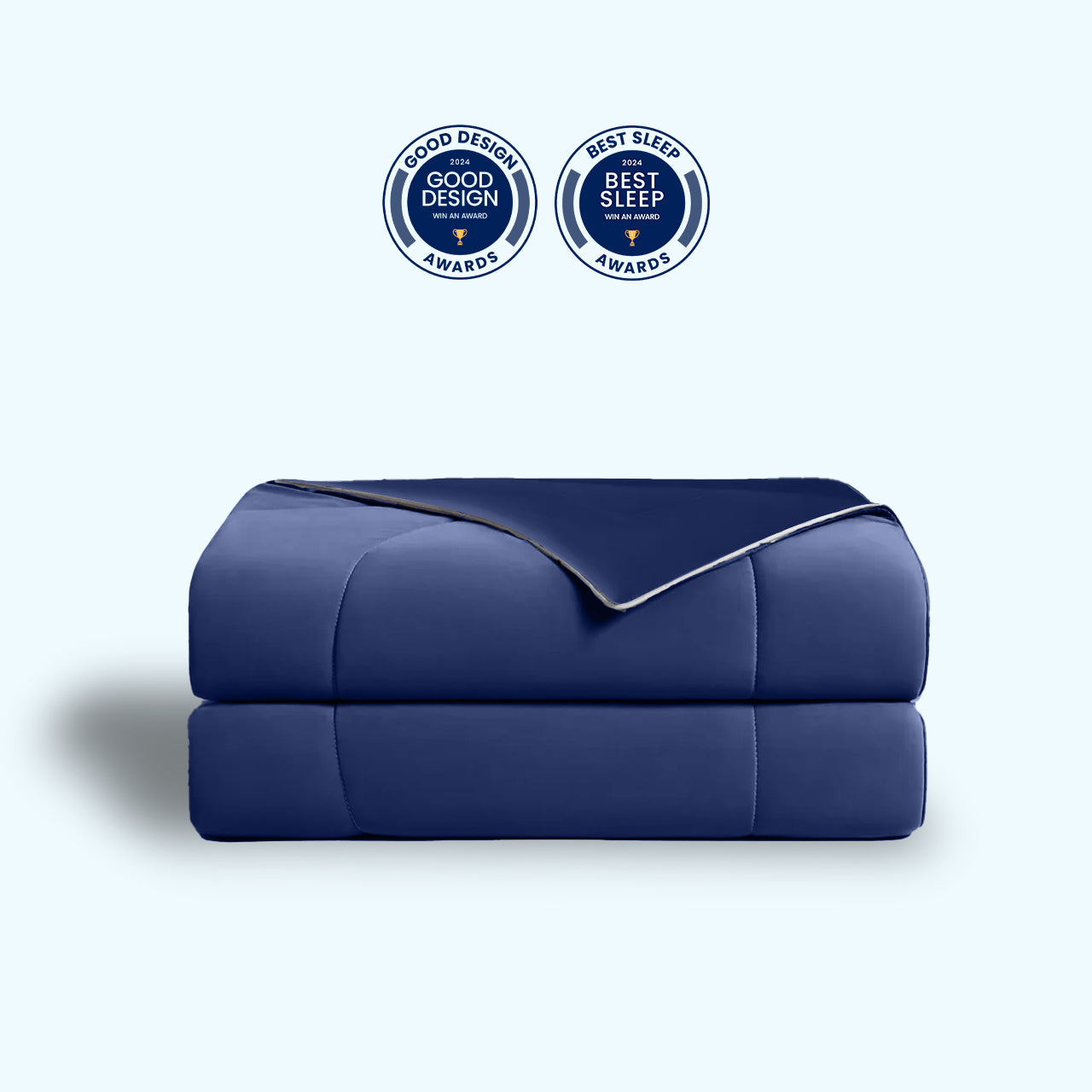 Dark-blue APSMILE cooling blanket with rounded "Good Design 2024" and "Best Sleep 2024" awards on top of it.