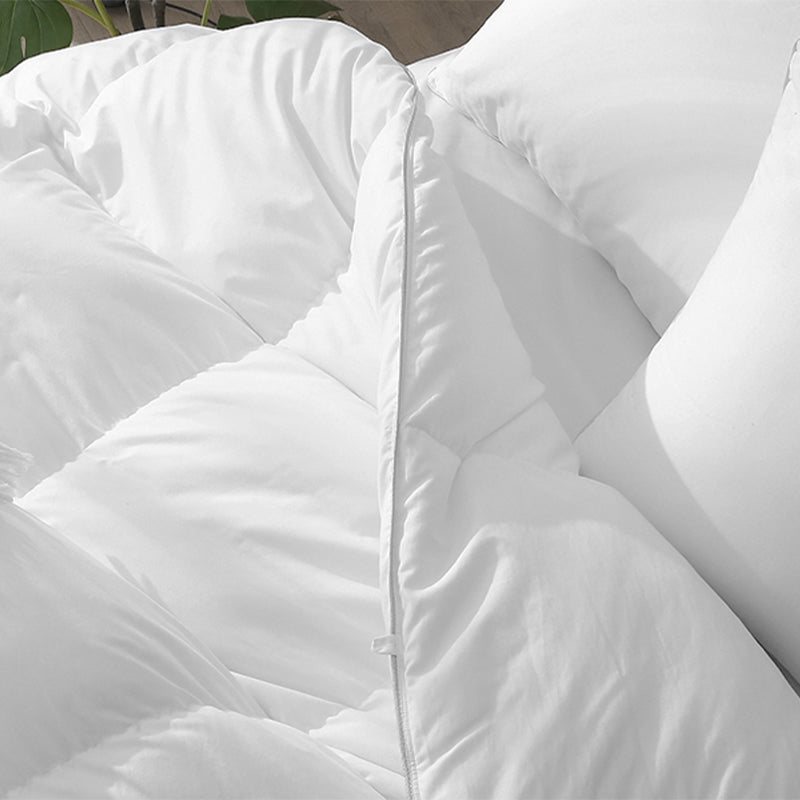 Close up of a puffy white duvet with a zipper closure.