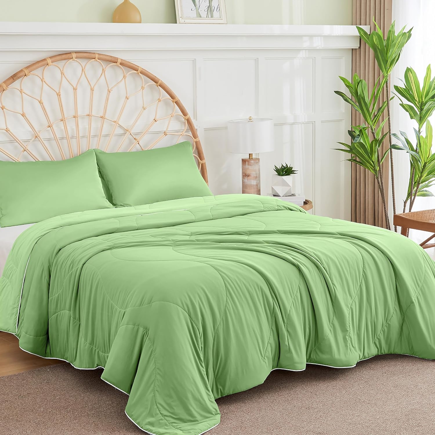 Close-up of an APSMILE cooling blanket in light green with white trim on a bed with pillows, against a backdrop of a white paneled wall and wicker headboard.