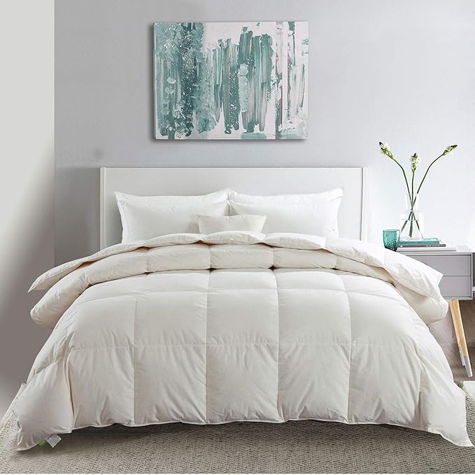 APSMILE white down comforter on a bed with white linens, complemented by an abstract painting and a bedside table with floral arrangement.
